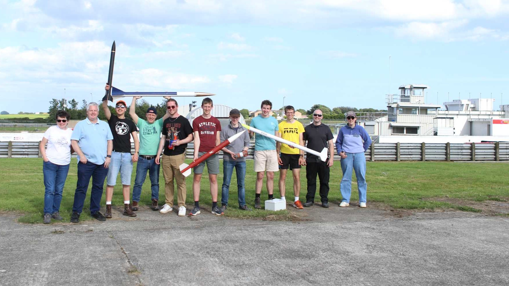 Group of people cheering holding model rockets from Ulster Rocketry launch in August